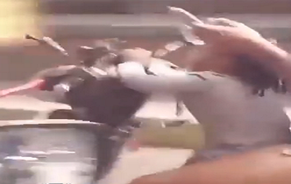 Una mujer maneja su moto por Petare con una bebé mientras revisa su teléfono