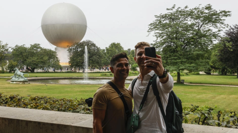 El pebetero olímpico ilumina los ojos de los turistas y el cielo de París